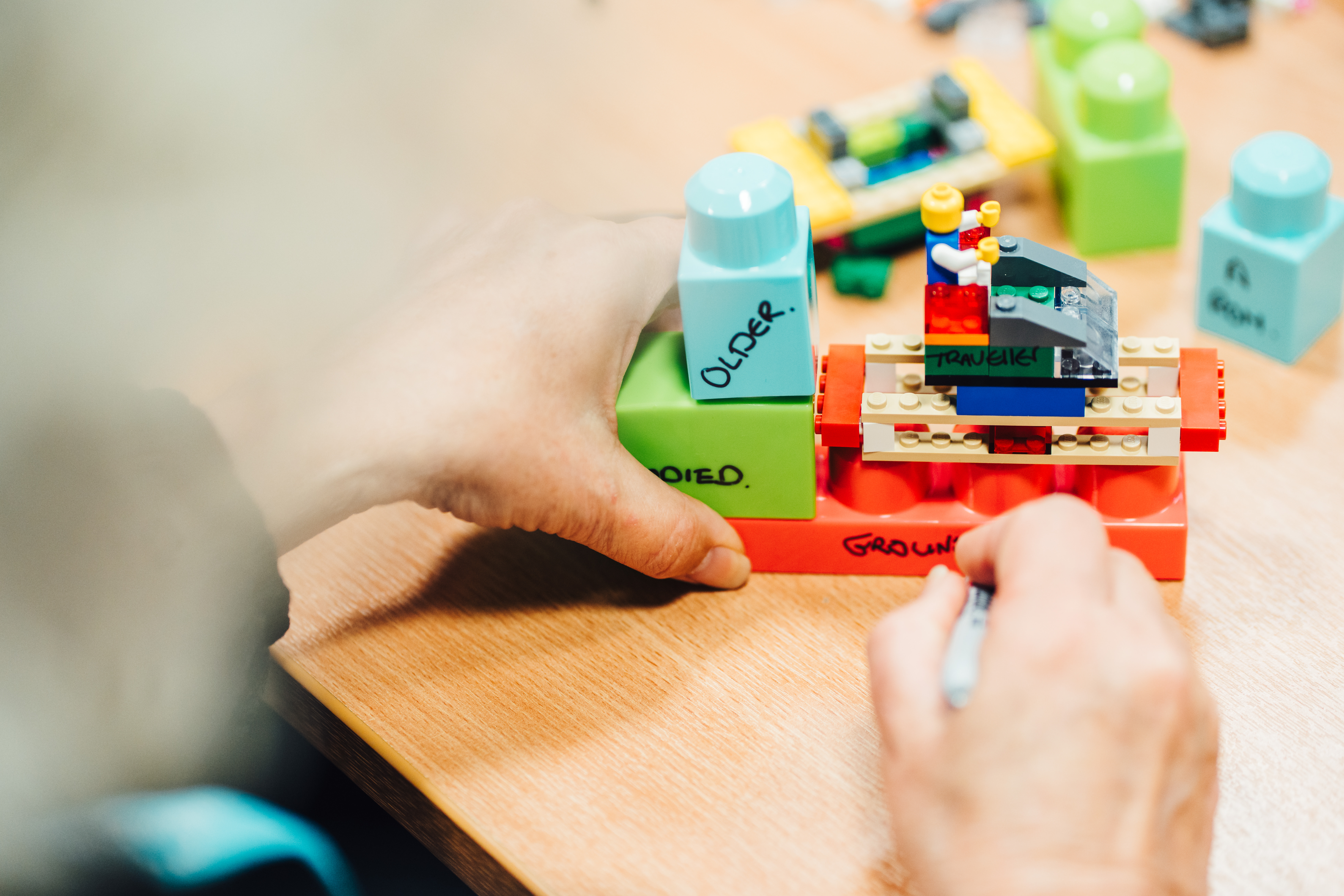 An image of a woman building lego and writing words on it to represent her