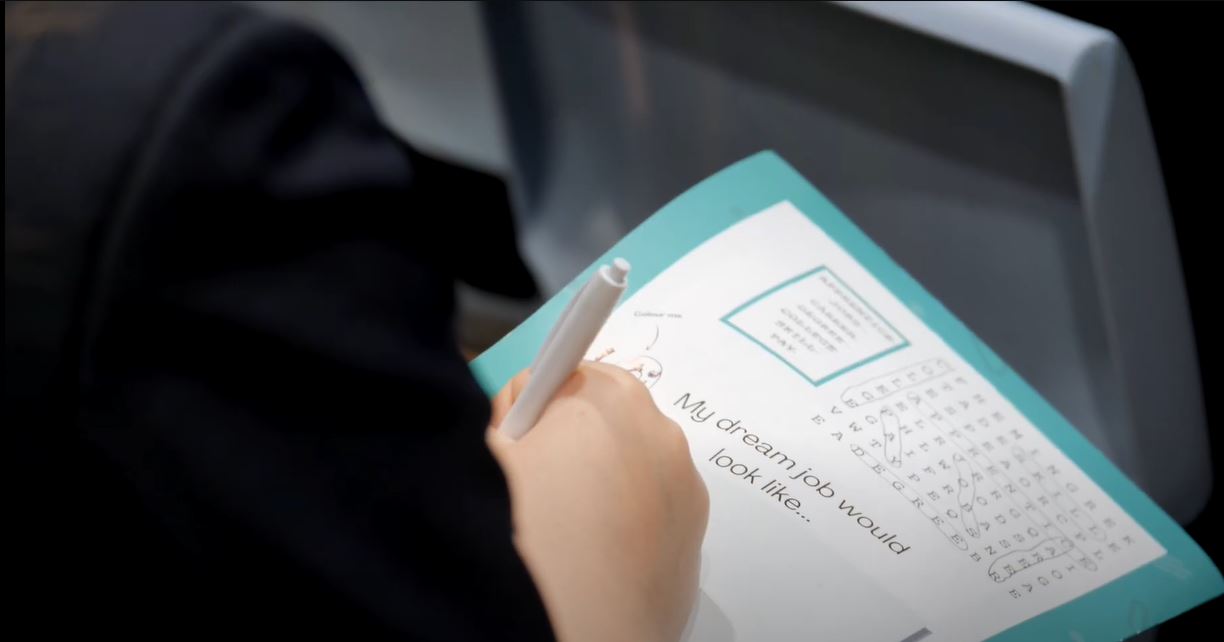 Still image of the Your Future Roadshow Promo Video - Close up of a student filling in an activity workbook
